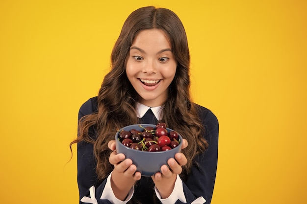 Teenager Kind Mädchen halten Platte Kirschen isoliert auf gelbem Hintergrund Sommer Beeren Kinder gesunde Kirschfrüchte Kirsche für Kinder