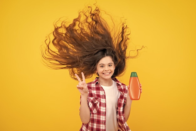 Teenager Kind Mädchen zeigt Flasche Shampoo Conditioner oder Duschgel Haarkosmetikprodukt Flasche für Werbespottkopienraum Fröhlicher Teenager positive und lächelnde Emotionen von Teenager-Mädchen