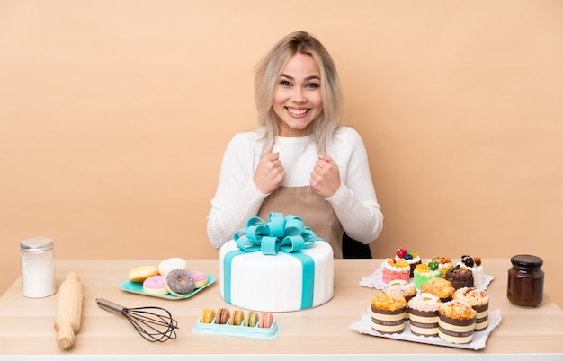 Teenager-Konditor mit einem großen Kuchen in einer Tabelle, die einen Sieg feiert