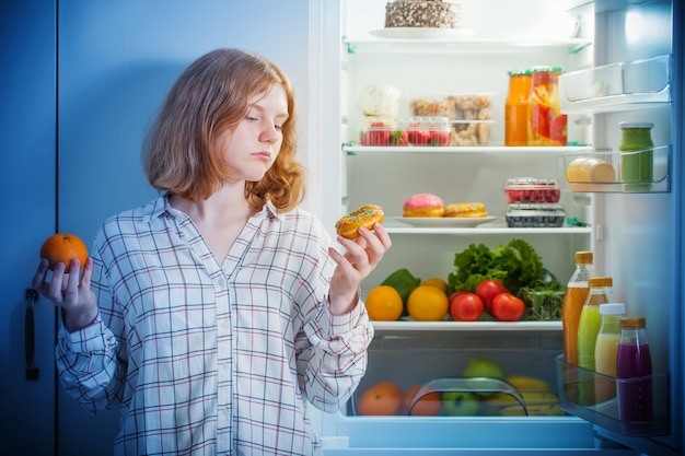 Teenager-Mädchen am Kühlschrank mit Essen