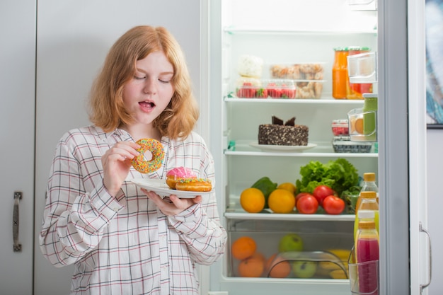 Teenager-Mädchen am Kühlschrank mit Essen