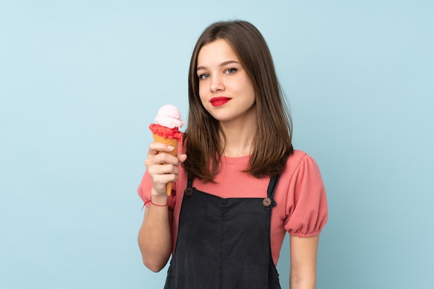 Teenager-Mädchen, das ein Kornett-Eis auf blauem Lächeln viel hält