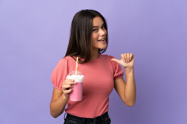 Teenager-Mädchen, das einen Erdbeermilchshake hält, der stolz und selbstzufrieden ist