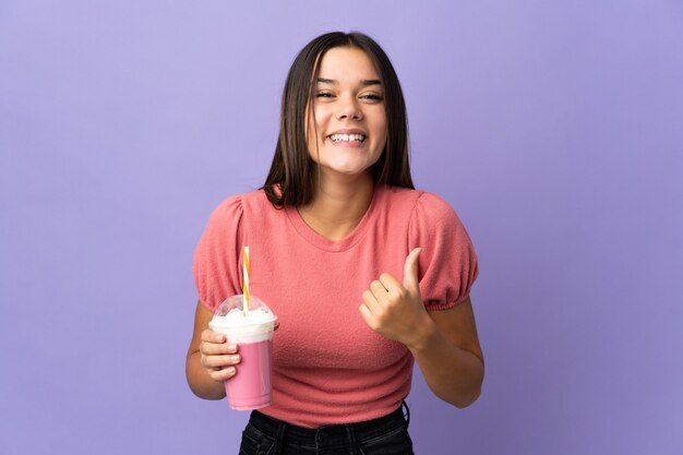 Teenager-Mädchen, das einen Erdbeermilchshake hält, der zur Seite zeigt, um ein Produkt zu präsentieren