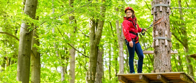 Foto teenager-mädchen, das im hochseilgarten oder im parl klettert