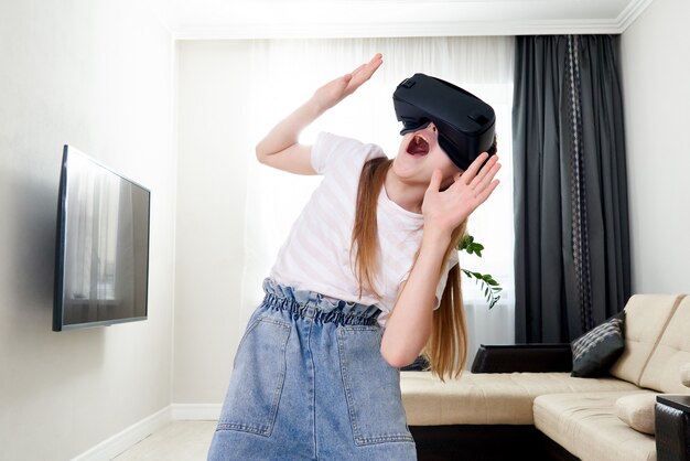 Teenager-Mädchen, das Virtual-Reality-Brillen-Headset trägt und spielt, VR-Box. Technologie, neue Generation, Fortschrittskonzept. Mädchen, das versucht, Objekte in der virtuellen Realität zu berühren.