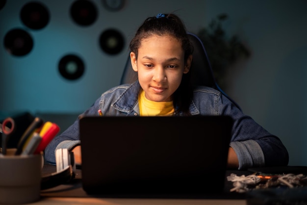 Teenager-Mädchen, das zu Hause online studiert und auf den Laptop schaut