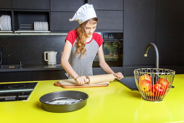 Foto teenager-mädchen, die teig vorbereiten, backen hausgemachten urlaub apfelkuchen in der küche