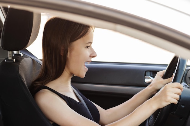Teenager-Mädchen fährt zum ersten Mal Auto, hat Angst davor, Auto zu fahren, winkt mit den Händen und schreit