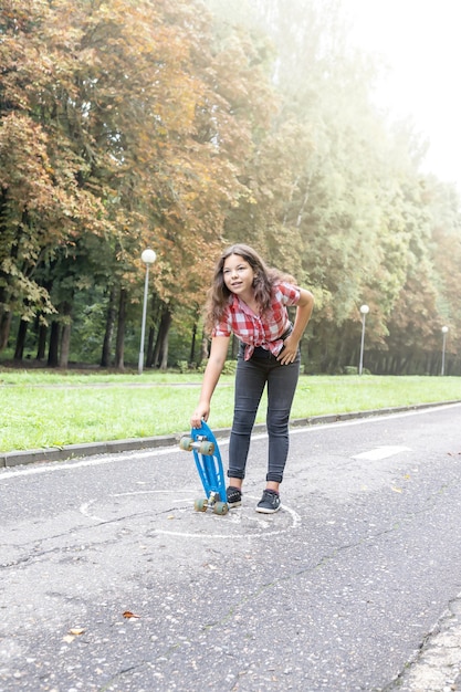 Teenager-Mädchen hält ein Skateboard in den Händen und freut sich