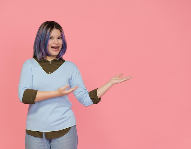 Foto teenager-mädchen heißt sie freundlich willkommen, lächelt und zeigt leeren kopierraum mit rosa händen