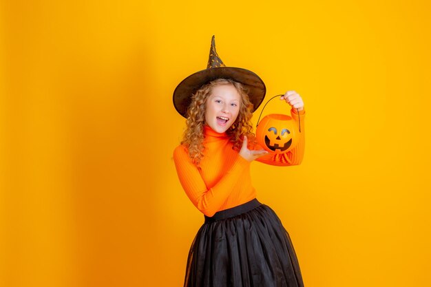 Teenager-Mädchen in einem Hexenkostüm auf gelbem Hintergrund Halloween