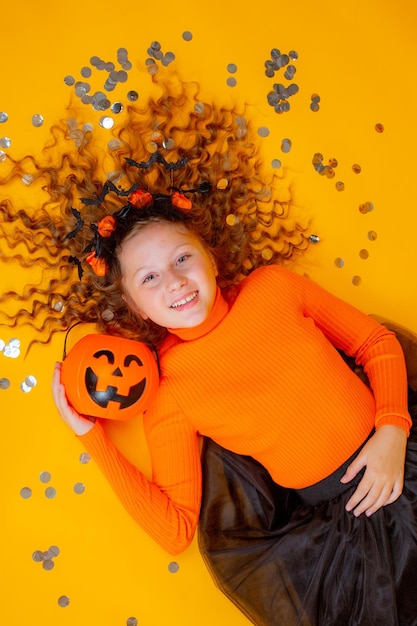 Teenager-Mädchen in einem Hexenkostüm auf gelbem Hintergrund Halloween