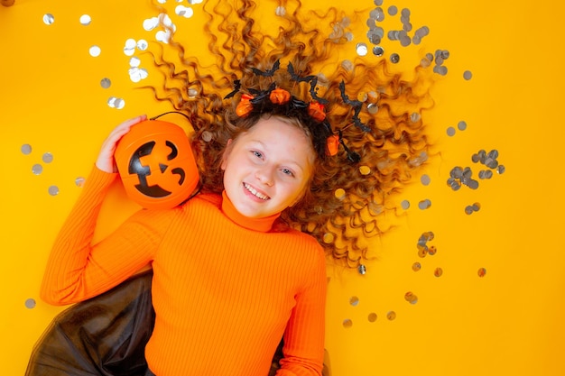 Teenager-Mädchen in einem Hexenkostüm auf gelbem Hintergrund Halloween