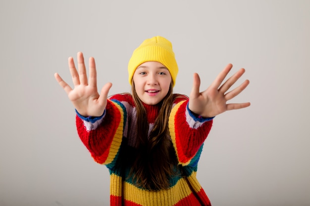 Teenager-Mädchen in einem Pullover und Hut auf einem weißen Hintergrund
