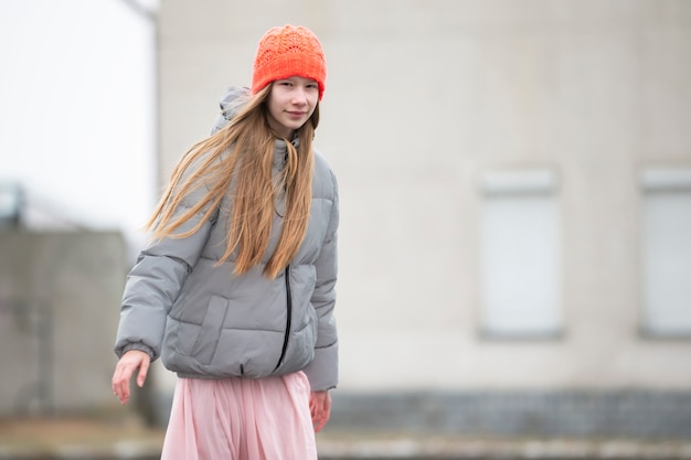 Teenager-Mädchen in Strickmütze und warmer Jacke vor dem Hintergrund der Stadt.