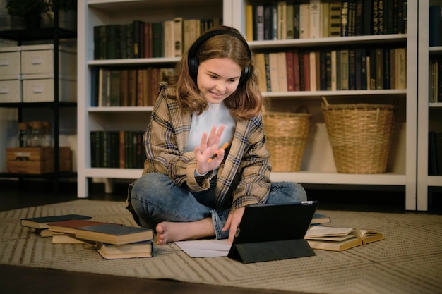 Foto teenager-mädchen macht hausaufgaben an einem schreibtisch in ihrem schlafzimmer. teenager-schülerin schreibt notizen, schaut sich ein video online an, ein webinar, lernt auf einem laptop, einen e-learning-kurs, eine videokonferenz, einen pc-anruf