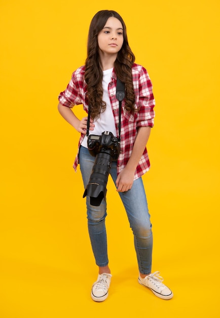 Teenager-Mädchen mit dslr-Fotokamera mit Zoomobjektiv Kinderfotograf isoalted auf gelbem Hintergrund Fotoschule Schießen mit professioneller Kamera