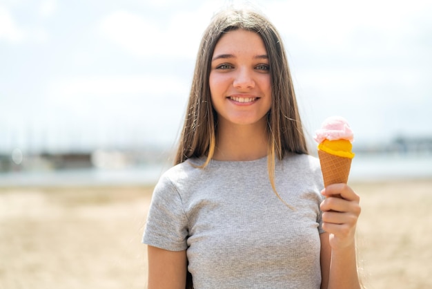 Teenager-Mädchen mit einem Cornet-Eis im Freien lächelt viel