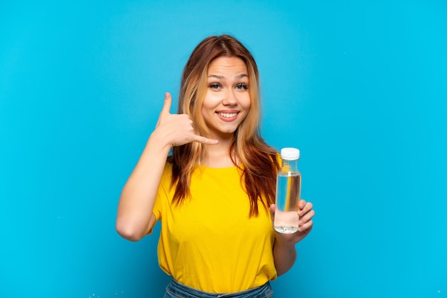 Teenager-Mädchen mit einer Flasche Wasser über lokalisiertem blauem Hintergrund, der Telefongeste macht. Rufen Sie mich zurück Zeichen