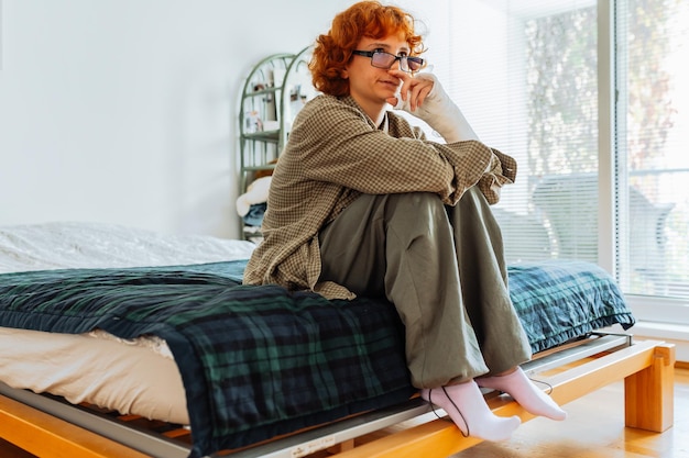 Teenager-Mädchen mit gebrochenem Arm, Brille und roten Haaren im Schlafzimmer