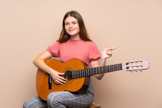 Teenager-Mädchen mit Gitarre zeigt auf die Seite, um ein Produkt zu präsentieren
