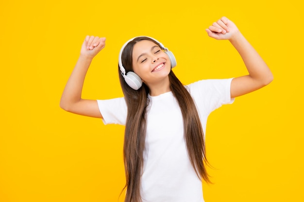 Teenager-Mädchen mit Kopfhörern Musik hören Zubehör für drahtlose Kopfhörer Das Kind genießt die Musik in den Kopfhörern auf gelbem Hintergrund