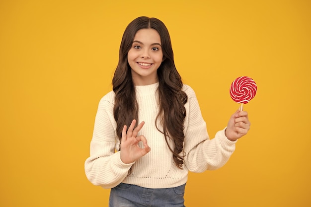 Teenager-Mädchen mit Lollipop-Kind, das Zuckerlutscher isst, Kinder, Süßigkeiten, Süßwarenladen Aufgeregtes Teenager-Mädchen Glückliches Gesicht, positive und lächelnde Emotionen von Teenager-Mädchen