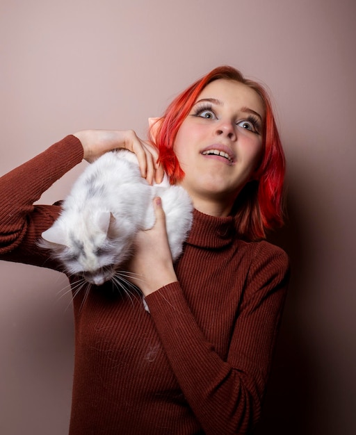 Teenager-Mädchen mit rosa Haaren, das eine weiße Katze in ihren Armen hält