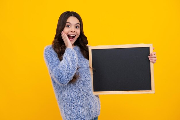 Teenager-Mädchen mit Tafel isoliert auf gelbem Hintergrund Erstaunt Teenager Aufgeregt Teenager