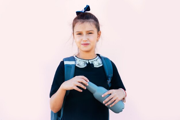 Teenager-Mädchen mit wiederverwendbarer Flasche auf rosa Hintergrund.