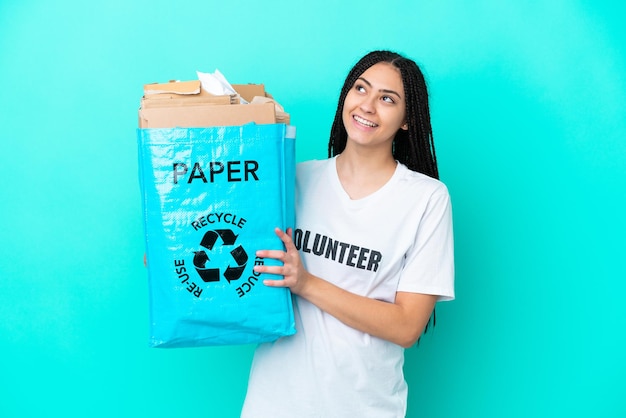 Teenager-Mädchen mit Zöpfen, die eine Tasche zum Recyceln halten und lächelnd aufschauen