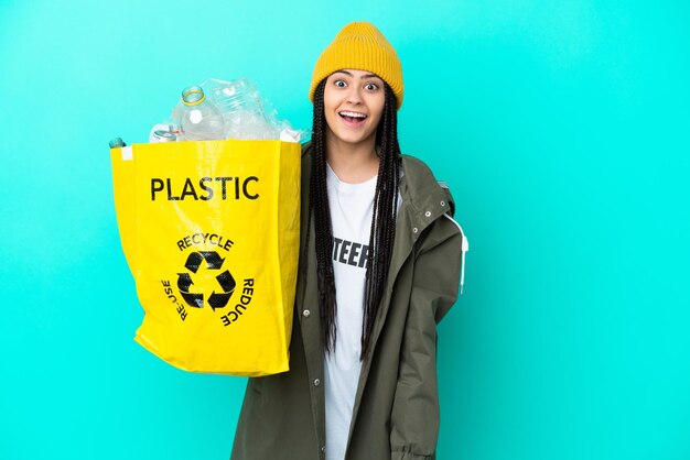 Teenager-Mädchen mit Zöpfen, die eine Tasche zum Recyceln mit überraschendem Gesichtsausdruck halten