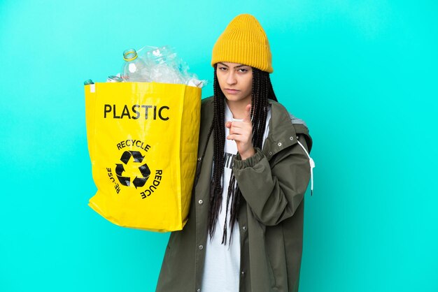 Teenager-Mädchen mit Zöpfen, die eine Tasche zum Recycling frustriert halten und nach vorne zeigen