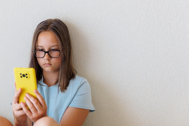 Teenager-Mädchen schaut auf das Telefon auf weißem Hintergrund