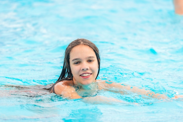 Teenager-Mädchen schwimmt im klaren blauen Wasser eines Pools während eines Urlaubs in einem warmen tropischen Land an einem sonnigen warmen Sommertag. Reisekonzept. Platz für Werbung