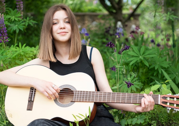 Teenager-Mädchen sitzt mit einer Gitarre