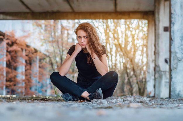 Foto teenager-mädchen sitzt mit gekreuzten beinen unterstützt kopf mit fäusten beinen gekreuzt der böse blick der blauen augen