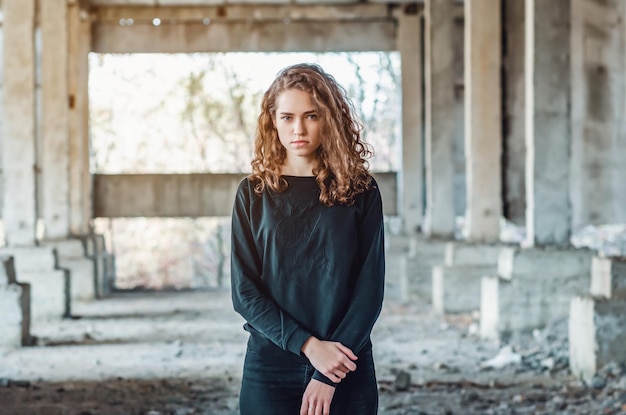 Teenager-Mädchen steht in einem verlassenen Gebäude Trauriger wütender Blick blauer Augen