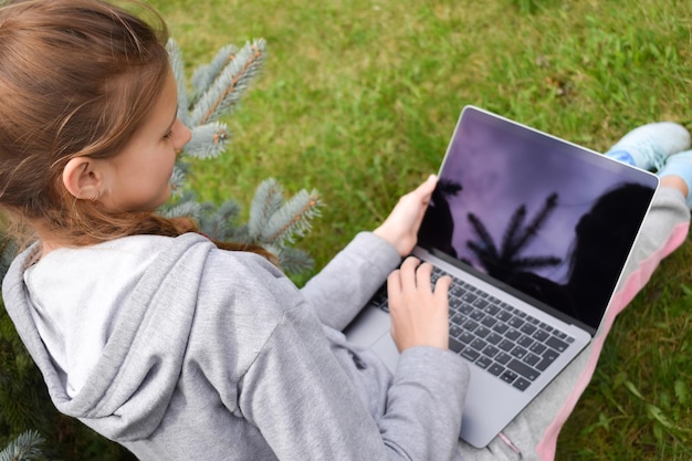 Teenager-Mädchen studiert auf einem Laptop Fernunterricht Glückliches Schulmädchen im Park mit Computer