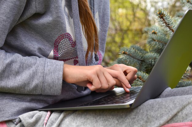 Teenager-Mädchen studiert auf einem Laptop Fernunterricht Glückliches Schulmädchen im Park mit Computer