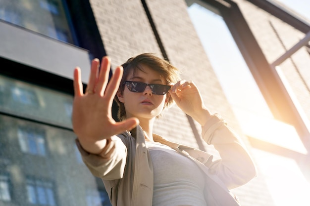 Teenager-Mädchen tragen eine stilvolle Brille, stehen auf der Stadtstraße und schauen in die Kamera