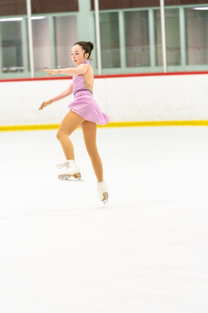 Teenager-Mädchen üben Eiskunstlauf auf einer Indoor-Eisbahn
