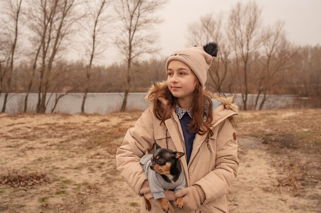 Teenager-Mädchen und Chihuahua-Hund. Mädchen im Schulalter und ihr Haustier im Park in der Natur. Liebe zu Tieren.