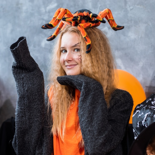 Teenager-Mädchen unter Dekor für Halloween-Feiertag, riesige Spinne auf dem Kopf. Nahaufnahme Foto, orange schwarze Farben