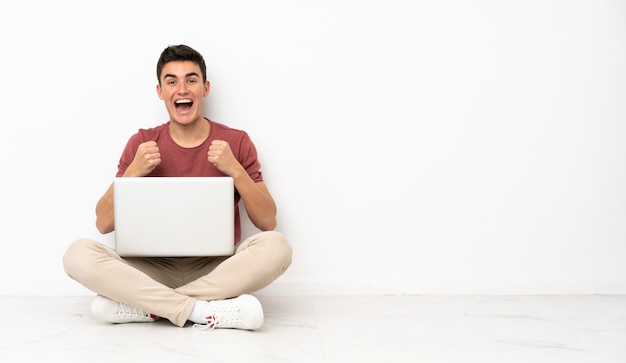 Teenager Mann sitzt auf dem Boden mit seinem Laptop frustriert von einer schlechten Situation