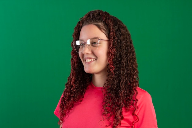 Teenager mit Brille in lustigen Posen auf einem Studiofoto mit grünem Hintergrund, ideal zum Zuschneiden