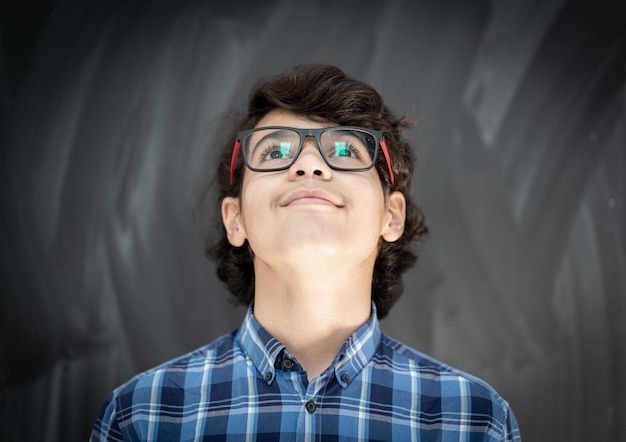 Teenager mit Brille vor der Tafel im Klassenzimmer