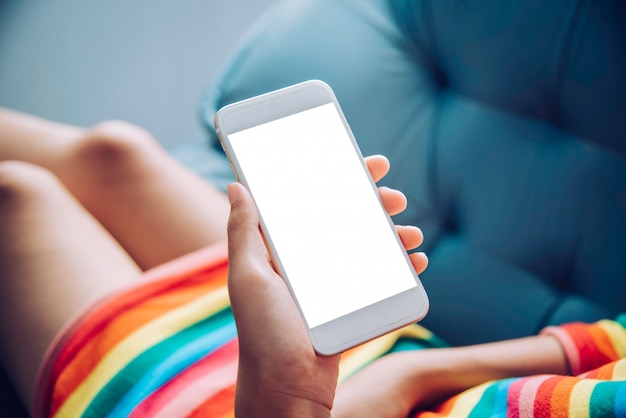 Teenager mit einem Handy auf dem Sofa in einem Wohnzimmer sitzen