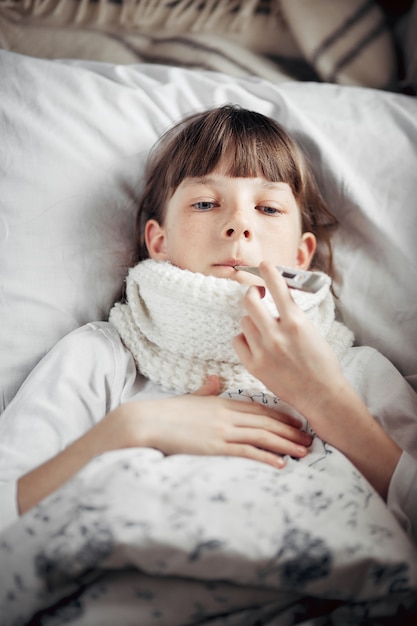 Teenager mit einer Erkältung misst die Temperatur